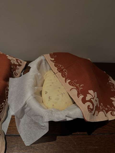 Een bol deeg met zaden rijst in een mand, half bedekt met een geborduurde theedoek